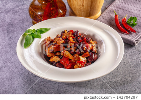 Hearty chicken and red bean stew in a white bowl, garnished with fresh basil Hearty chicken and red bean stew in a white bowl, garnished with fresh basil 142704297