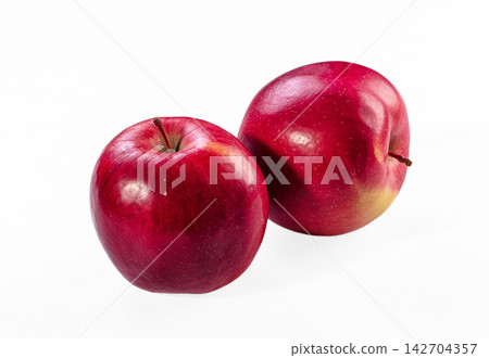 Two shiny red apples with natural stems on clean white background, smooth skin texture and soft highlights 142704357