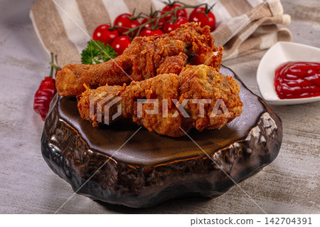 Crispy fried chicken legs on rustic ceramic plate with cherry tomatoes and ketchup Crispy fried chicken legs on rustic ceramic plate with cherry tomatoes and ketchup 142704391