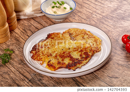 Crispy golden potato pancakes served on white plate with sour cream and chives Crispy golden potato pancakes served on white plate with sour cream and chives 142704393