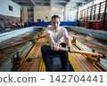 Focused male rower applying strength and endurance during demanding indoor rowing tank workout 142704441