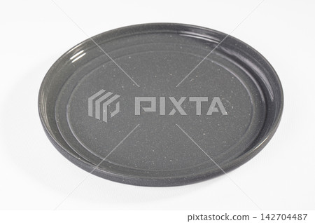 Round dark gray speckled ceramic plate on white background, shallow depth of field, soft studio lighting, minimalist composition with copy space Round dark gray speckled ceramic plate on white background, shallow depth of field, soft studio lighting, minimalist composition with copy space 142704487