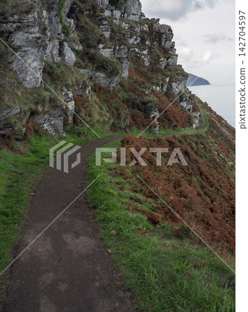 Coastal Path winding around rugged cliffs, Valley of Rocks, Exmoor, Devon Coastal Path winding around rugged cliffs, Valley of Rocks, Exmoor, Devon 142704597