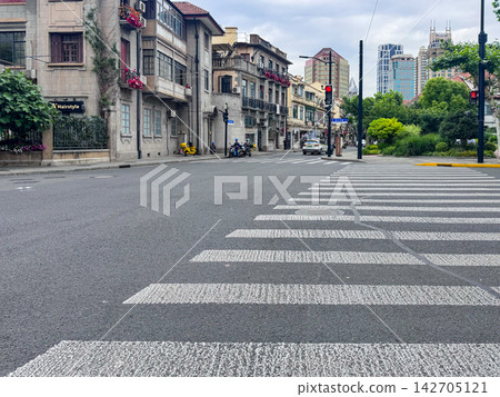A Quiet Urban Scene Featuring a Crosswalk and Surrounding Architecture Amidst a Calm Overcast Day in a Busy City A Quiet Urban Scene Featuring a Crosswalk and Surrounding Architecture Amidst a Calm Overcast Day in a Busy City 142705121