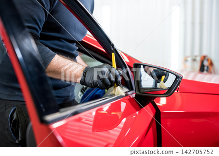 Car service worker cleans interiror with special brush 142705752