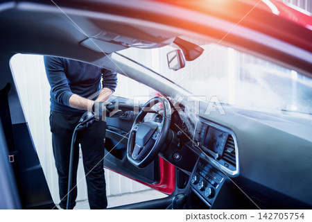 Car service worker cleans interiror with steam cleaner 142705754