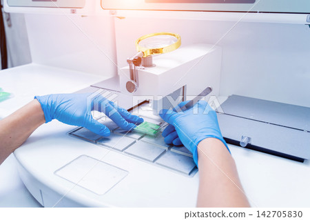 Laboratory assistant works at paraffin wax dispenser tissue embedding machine. Laboratory assistant works at paraffin wax dispenser tissue embedding machine. 142705830