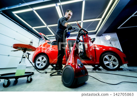 Car service worker cleaning car seat with a steam cleaner Car service worker cleaning car seat with a steam cleaner 142705863