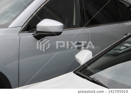 Comparison of the height of a large SUV and a regular sedan parked next to it 142705919