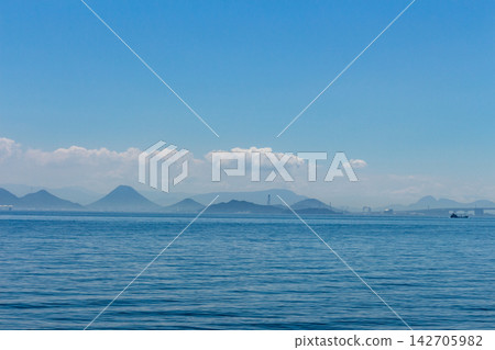 遠處是瀨戶內海，遠處有島嶼和橋樑，天空湛藍平靜，海面波光粼粼，遠處群山綿延。 142705982