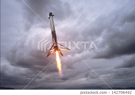 3D illustration of a Falcon reusable rocket booster performing a vertical landing with powerful engine flames against a dramatic cloudy sky. 3D illustration of a Falcon reusable rocket booster performing a vertical landing with powerful engine flames against a dramatic cloudy sky. 142706492