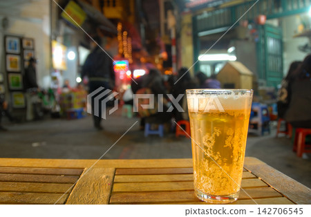 Hanoi, Vietnam: A glass of beer sitting on a table in the old quarter of Hanoi at night. Blurred background with no recognisable people or property Hanoi, Vietnam: A glass of beer sitting on a table in the old quarter of Hanoi at night. Blurred background with no recognisable people or property 142706545