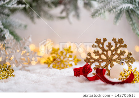 Golden Snowflakes with Red Ribbon and White Ornament on Snow Golden Snowflakes with Red Ribbon and White Ornament on Snow 142706615