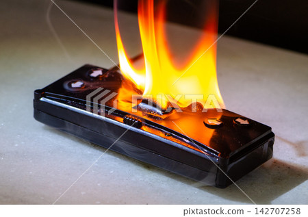 Burning remote control device with fire and sparks as fire threat and damage concept Burning remote control device with fire and sparks as fire threat and damage concept 142707258