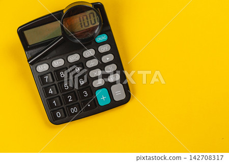 Using a magnifying glass to inspect a calculator on a bright table Using a magnifying glass to inspect a calculator on a bright table 142708317