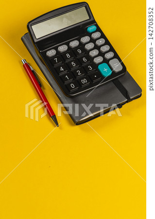 Calculator and notebook on a yellow desk for financial planning tasks Calculator and notebook on a yellow desk for financial planning tasks 142708352