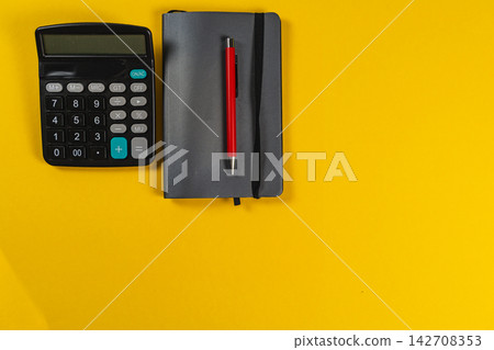 Calculator and notebook on yellow desk during business planning Calculator and notebook on yellow desk during business planning 142708353