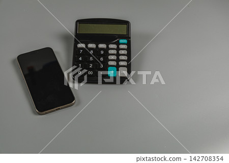 Calculator and smartphone placed on a gray surface for business tasks Calculator and smartphone placed on a gray surface for business tasks 142708354