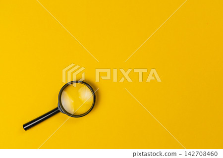 Magnifying glass on a yellow background with a focus on an object Magnifying glass on a yellow background with a focus on an object 142708460