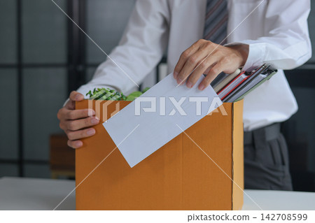 Businessman quitting job submitting resignation letter and packing personal belongings into cardboard box ready to leaving company. Businessman quitting job submitting resignation letter and packing personal belongings into cardboard box ready to leaving company. 142708599
