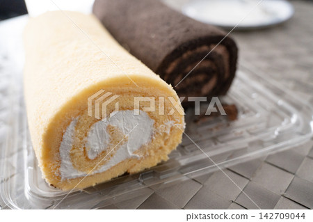 餐桌上的場景,擺放著兩種蓬鬆的捲蛋糕。 餐桌上的場景,擺放著兩種蓬鬆的捲蛋糕。 142709044