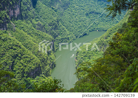 Scenic landscape showing the green Grijalva River winding through Sumidero Canyon in Chiapas Mexico with steep canyon walls lush landscape river overlook nature tourism and a wide scenic view. Scenic landscape showing the green Grijalva River winding through Sumidero Canyon in Chiapas Mexico with steep canyon walls lush landscape river overlook nature tourism and a wide scenic view. 142709139