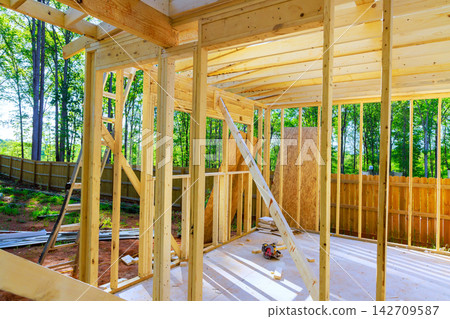 Construction site wooden framework in progress near wooded area Construction site wooden framework in progress near wooded area 142709587