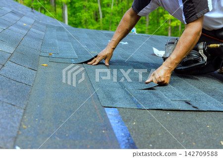 Roofing work is done on house in wooded area Roofing work is done on house in wooded area 142709588