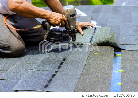 Roofing work in progress on house with shingles being installed Roofing work in progress on house with shingles being installed 142709589