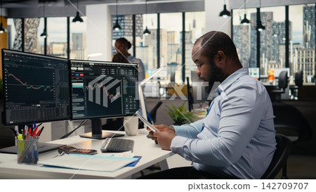Anxious portfolio manager worried by negative investment returns. Upset African american man distressed by low performance metrics, failing to capitalize on investment fluctuations Anxious portfolio manager worried by negative investment returns. Upset African american man distressed by low performance metrics, failing to capitalize on investment fluctuations 142709707