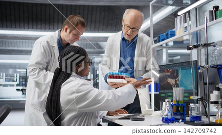 Colleagues examining a blood sample tube for analysis and testing, biotechnology research emphasizes genetics and molecular science. Advanced medicine and innovation in laboratory. Colleagues examining a blood sample tube for analysis and testing, biotechnology research emphasizes genetics and molecular science. Advanced medicine and innovation in laboratory. 142709742