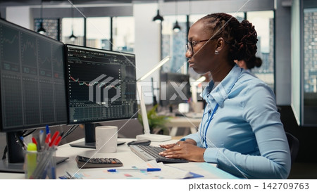 Trader frowning while looking at investment portfolio candlestick charts after unexpected market crash. African american woman upset by stock exchange account losses Trader frowning while looking at investment portfolio candlestick charts after unexpected market crash. African american woman upset by stock exchange account losses 142709763