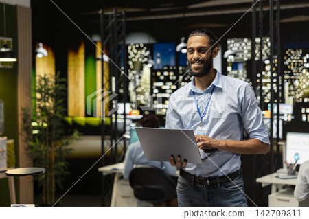 Smiling Arab employee standing in office, reading emails on laptop screen, responding to inbox messages. Happy man analyzing data on notebook display at night, interpreting statistical information Smiling Arab employee standing in office, reading emails on laptop screen, responding to inbox messages. Happy man analyzing data on notebook display at night, interpreting statistical information 142709811