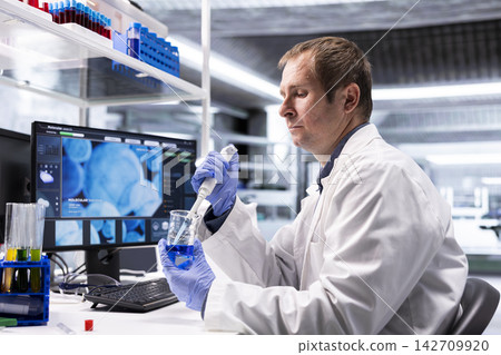 Professional chemistry scientist works in biolab with pipette and jar, preparing chemical mixture. Laboratory procedure emphasizes molecular biology and bioengineering in medical research. Professional chemistry scientist works in biolab with pipette and jar, preparing chemical mixture. Laboratory procedure emphasizes molecular biology and bioengineering in medical research. 142709920