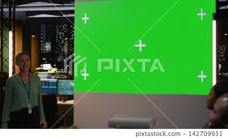 Diverse staff pitching proposals to stakeholders next to mockup during a business meeting in a dark office, late night conference to discuss budget updates, company objectives with insight. Camera A. 142709931