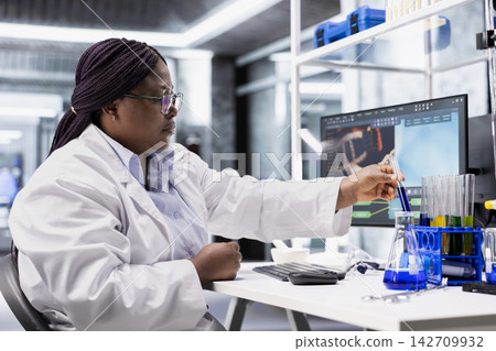 Woman scientist examines experiment data in a modern laboratory, driving progress in healthcare technology and clinical testing. Biotechnology research, pharmacology and digital health. 142709932