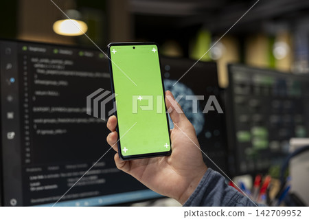 Close up of system administrator using green screen smartphone, debugging app issues and improving system stability. IT expert in tech company office typing on mockup mobile phone Close up of system administrator using green screen smartphone, debugging app issues and improving system stability. IT expert in tech company office typing on mockup mobile phone 142709952