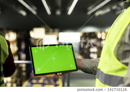 Green screen tablet, warehouse employee, handling cargo, distribution operations. Manual labor supporting shipping management and inventory control for large business supply chain. Green screen tablet, warehouse employee, handling cargo, distribution operations. Manual labor supporting shipping management and inventory control for large business supply chain. 142710126