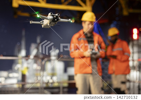 Selective focus of skilled drone pilot ensuring aerial surveillance of oil rig, using radar systems and remote control gadgets to inspect industrial equipment and oil industry infrastructure. Selective focus of skilled drone pilot ensuring aerial surveillance of oil rig, using radar systems and remote control gadgets to inspect industrial equipment and oil industry infrastructure. 142710132