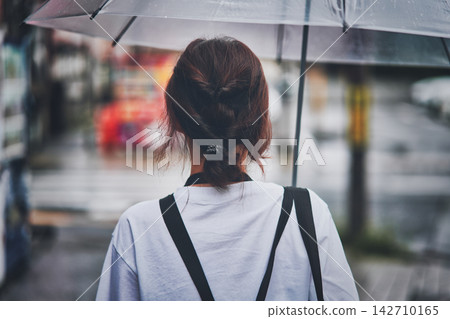 The back view of a woman holding an umbrella. The back view of a woman holding an umbrella. 142710165