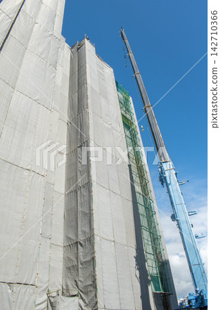 建築工地,一台起重機正在吊起建築物。 建築工地,一台起重機正在吊起建築物。 142710366