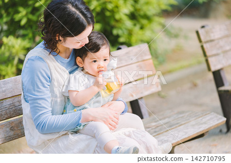 A mother playing with her baby in the park A mother playing with her baby in the park 142710795
