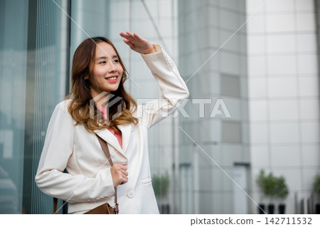 businesswoman standing outside office building in city raise your hand to shade the sun businesswoman standing outside office building in city raise your hand to shade the sun 142711532