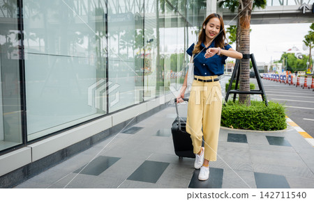 Woman waiting for her flight at the airport terminal with her luggage Woman waiting for her flight at the airport terminal with her luggage 142711540