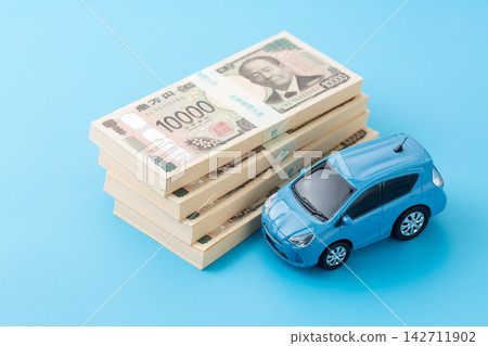 A blue car and a stack of 4 million yen bills against a blue screen. A blue car and a stack of 4 million yen bills against a blue screen. 142711902