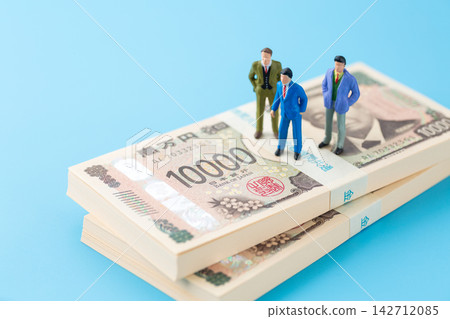 一疊價值 200 萬日圓的鈔票和一個穿著西裝的商人模特兒。 一疊價值 200 萬日圓的鈔票和一個穿著西裝的商人模特兒。 142712085