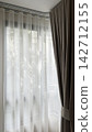 Luxury beige ripple fold curtains with white sheer on a curved track and sunlight 142712155