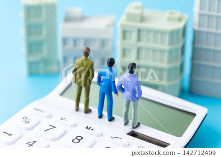 A mannequin of a businessman in a suit, a calculator, and an office building. A mannequin of a businessman in a suit, a calculator, and an office building. 142712409