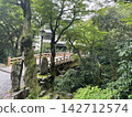 一座橋，橋邊有木質欄桿，周圍有綠樹。 142712574