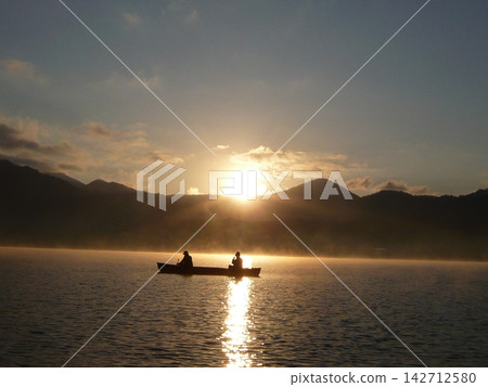 一艘小船緩緩滑過霧氣瀰漫的湖面。 一艘小船緩緩滑過霧氣瀰漫的湖面。 142712580